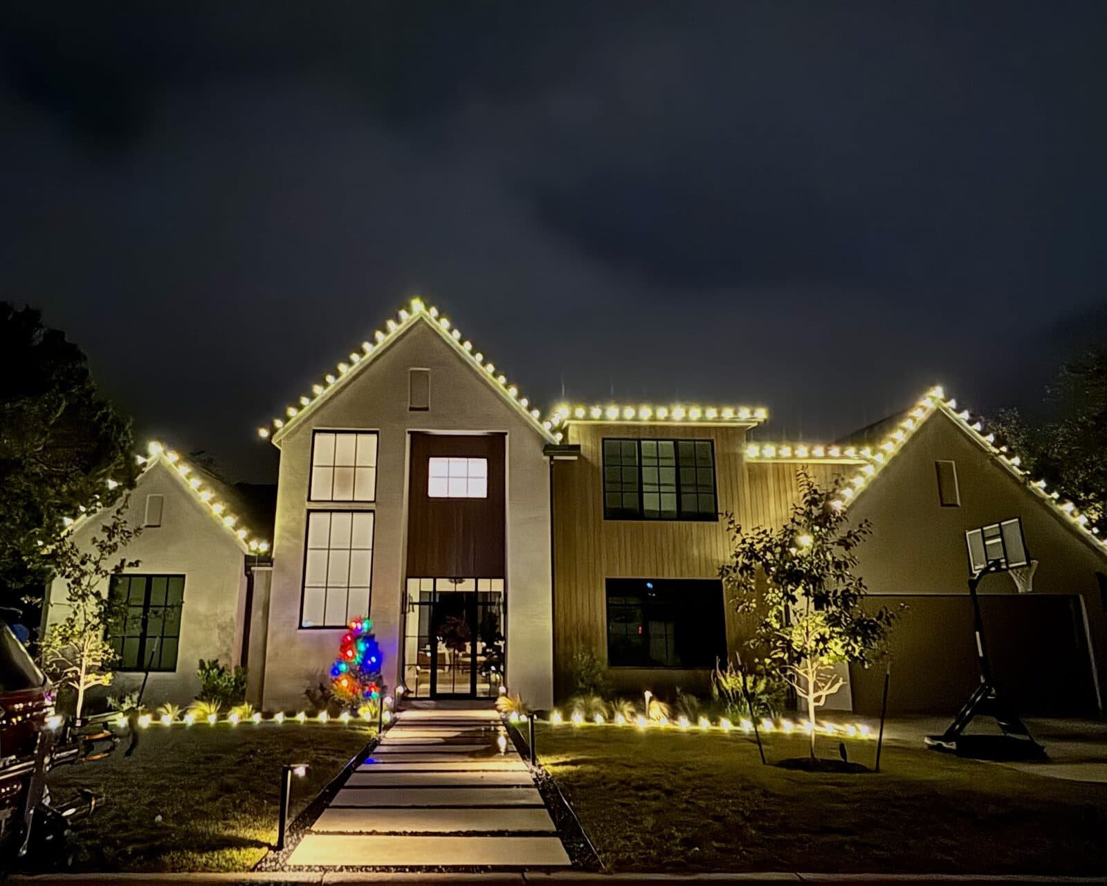 Detail of warm white Christmas lights against an evening sky